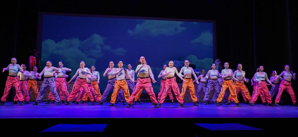 A large dance crew of 28+ teenage girls in the middle of a performance.