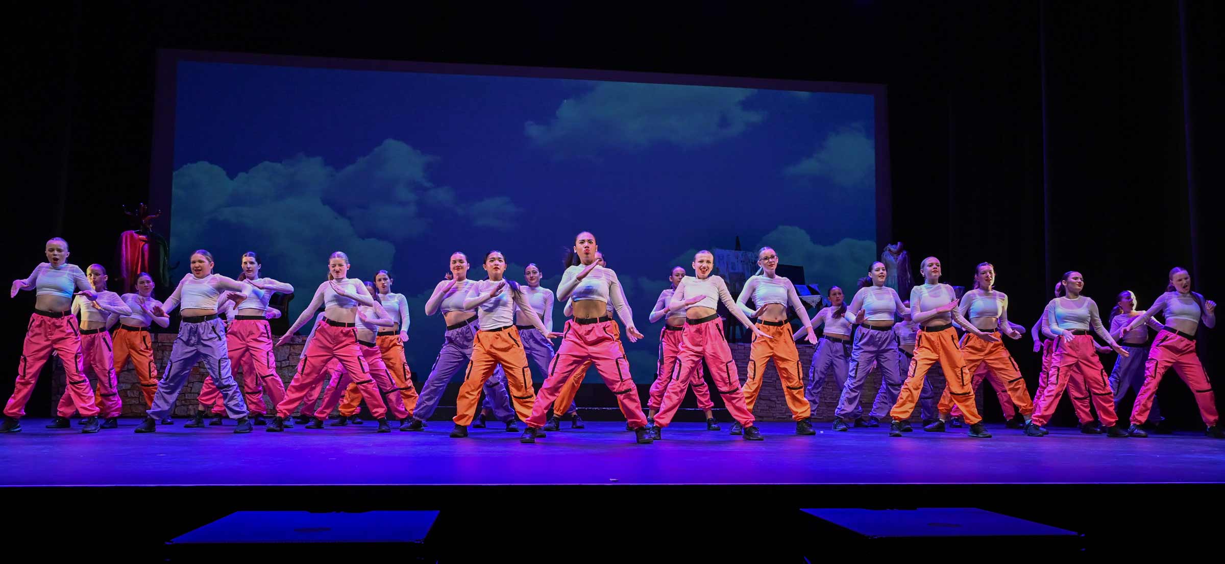 A large dance crew of 28+ teenage girls in the middle of a performance.