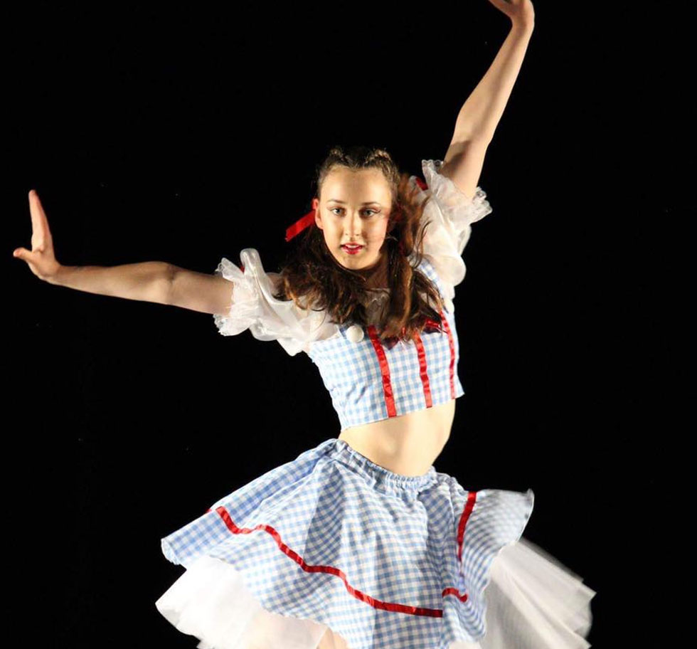 A dancer on stage dressed as Dorothy from Wizard of Oz